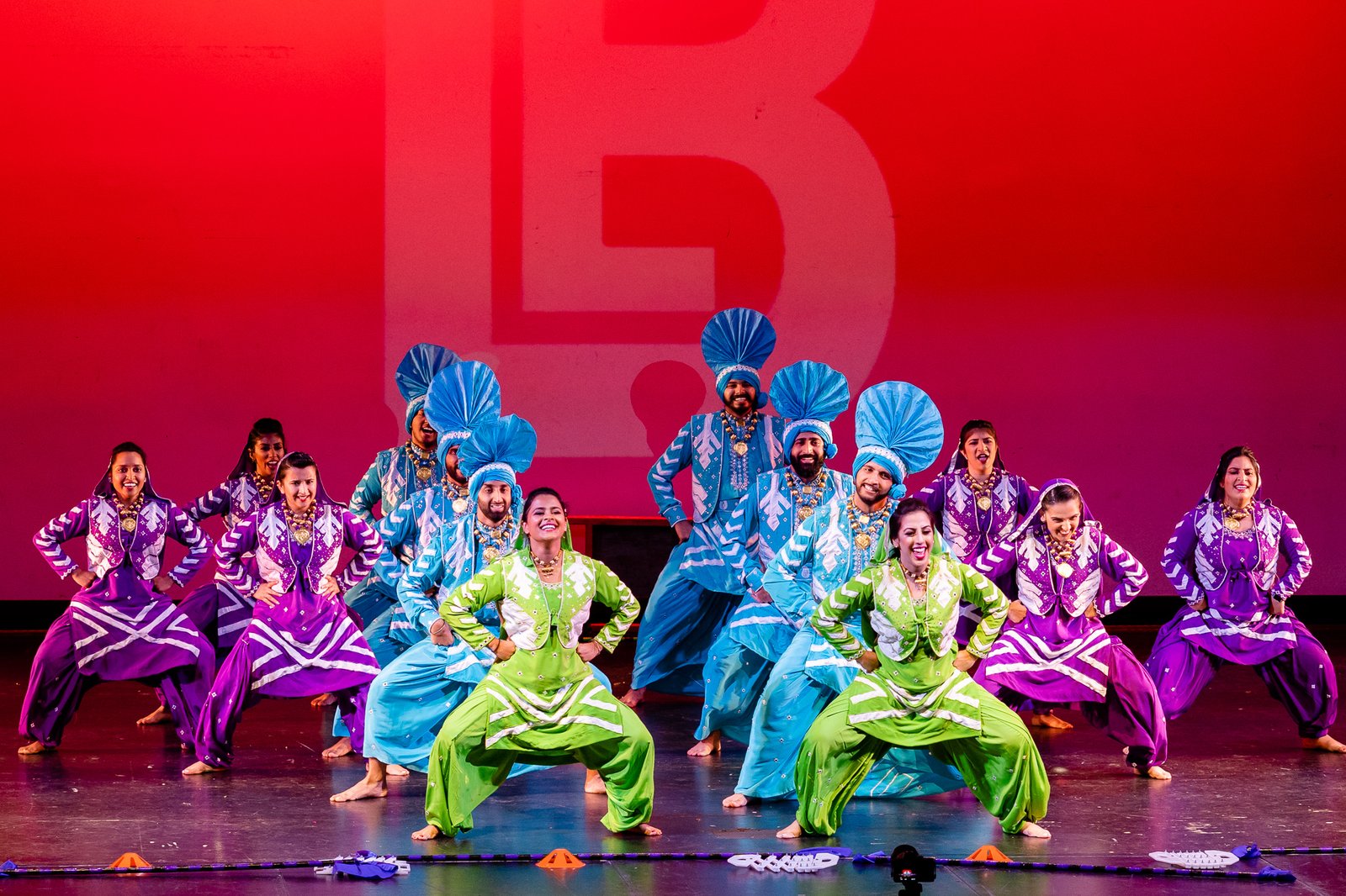 Students performing Bhangra together under the lights on an indoor Dance Off stage