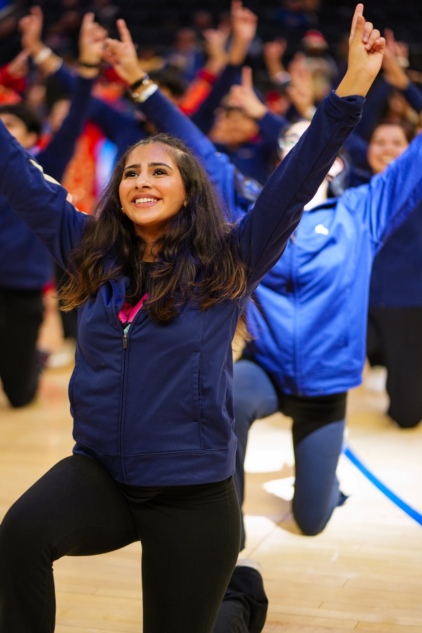 An Academy dancer smiling with both arms raised during the Warriors performance.